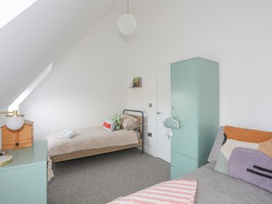 A bedroom with two beds a green cabinet and a small shelf on the wall at Ysgol Fawr (Big School) in Benllech