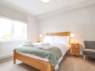 A bedroom with a wooden bed and white bedding at 1 Millbank in Keswick