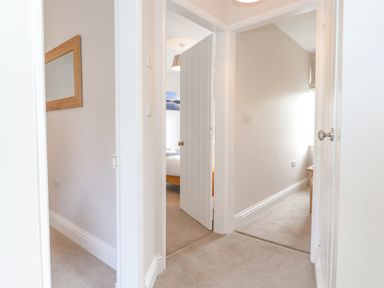 A hallway with beige carpet leading to rooms with white doors and cream walls at 1 Millbank in Keswick