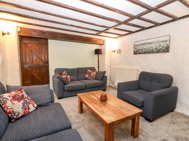 A living room with three sofas a wooden coffee table and a wooden door at Is Y Graig in Beddgelert
