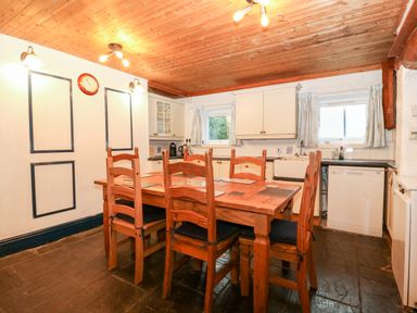 A kitchen with wooden dining table and chairs white cabinets and a dishwasher at Is Y Graig in Beddgelert
