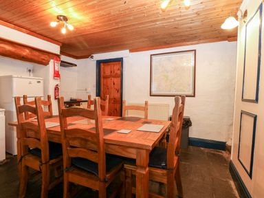A dining area with wooden table and chairs a refrigerator and a map on the wall at Is Y Graig in Beddgelert