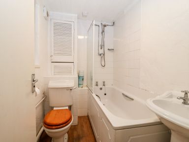 A bathroom with a bathtub shower toilet with wooden seat and a sink at Is Y Graig in Beddgelert