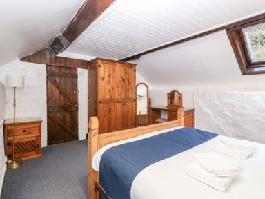 A bedroom with wooden furniture including a bed wardrobe dressing table and bedside table at Is Y Graig in Beddgelert