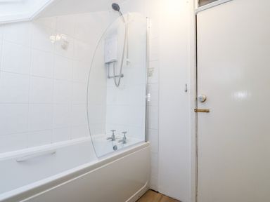 A bathroom with a bathtub shower combination and a door at Is Y Graig in Beddgelert