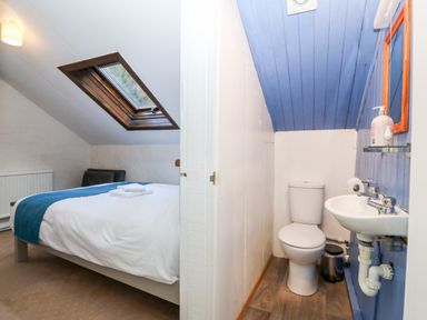 A bedroom with a bed and skylight window next to a small bathroom with toilet and sink at Is Y Graig in Beddgelert