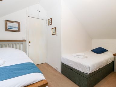 A bedroom with two single beds a door and framed pictures on the walls at Is Y Graig in Beddgelert