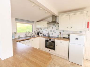 A kitchen with wooden countertops white cabinets a refrigerator oven and a window with a view at Siesta Chalet in Eype Mouth Chalet Park