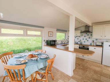 A kitchen with a dining table set with bread and tableware at Siesta Chalet in Eype Mouth Chalet Park