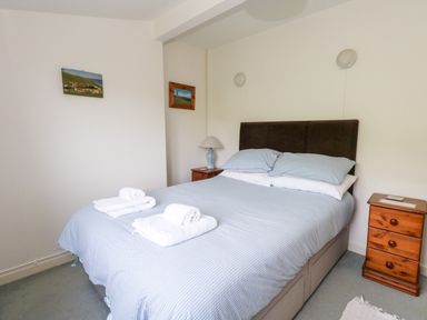 A bedroom with a double bed with blue bedding and two bedside tables with lamps at Siesta Chalet in Eype Mouth Chalet Park