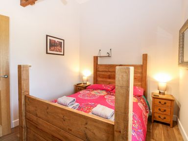 A bedroom with a wooden bed and two bedside tables with lamps at The Barnhouse in Felmingham near North Walsham
