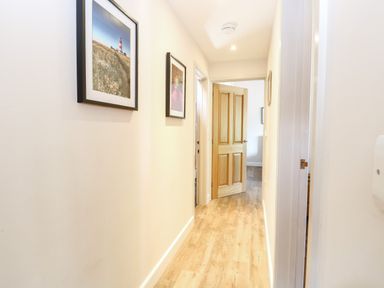 A hallway with wooden floor and two framed pictures on the wall at The Barnhouse in Felmingham near North Walsham