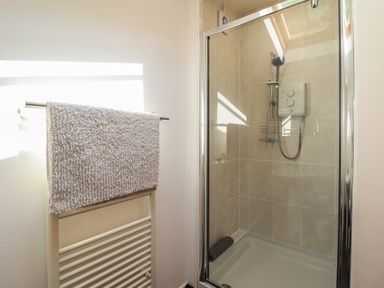 A bathroom with a shower enclosure and a towel hanging on a radiator at Llygoden Cottage in Beddgelert