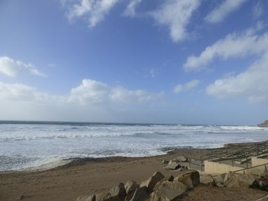 A beach with waves and rocks near a concrete ramp with railings at Puddle Duck Shepherds Hut in Crackington Haven