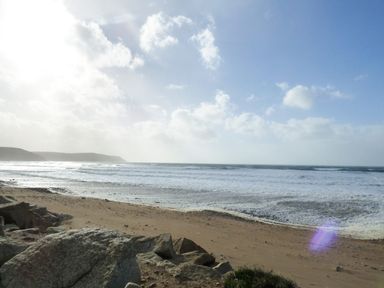 A sandy beach with rocks and waves under a blue sky at Shepherds Retreat in Maxworthy near Crackington Haven