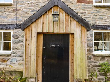 A black door with a wooden porch and a lantern on a stone house at Pen y Bont Near Mallwyd