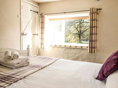 A bedroom with a bed folded towels a window with curtains and a door at Pen y Bont Near Mallwyd