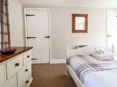 A bedroom with a white bed with towels on it a dresser with a bowl and a mirror on the wall at Pen y Bont Near Mallwyd