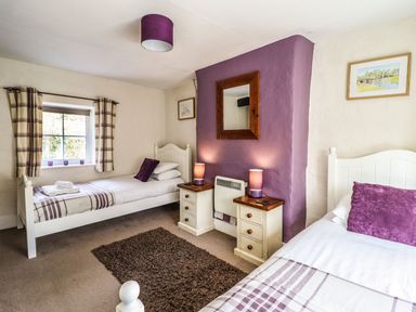 A bedroom with two single beds bedside tables lamps and a window at Pen y Bont Near Mallwyd