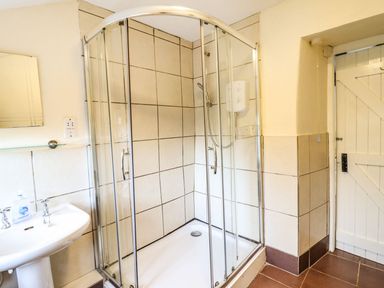 A bathroom with a glass shower enclosure sink and a wooden door at Pen y Bont Near Mallwyd