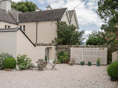 A gravel courtyard with wooden chairs a table potted plants and a white wooden fence at The Old Rectory Coach House in Rathmullan County Donegal