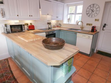 A kitchen with wooden countertops a microwave a toaster a sink and a wall clock at The Old Rectory Coach House in Rathmullan County Donegal