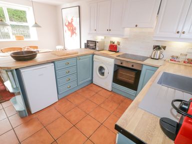 A kitchen with blue lower cabinets white upper cabinets wooden countertops and tiled floor at The Old Rectory Coach House in Rathmullan County Donegal