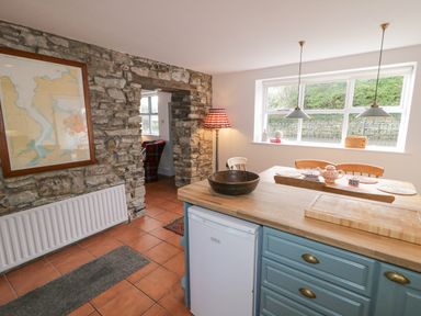 A kitchen and dining area with a stone wall and framed map at The Old Rectory Coach House in Rathmullan County Donegal