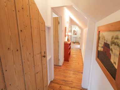 A hallway with wooden floors cabinets and a red shelf with a lamp at The Old Rectory Coach House in Rathmullan County Donegal