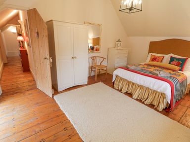 A bedroom with a bed pillows wardrobe chair dresser and rug at The Old Rectory Coach House in Rathmullan County Donegal