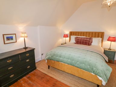 A bedroom with a bed a chest of drawers and lamps at The Old Rectory Coach House in Rathmullan County Donegal