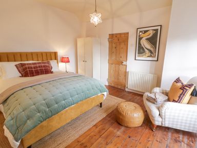 A bedroom with a bed a chair a wooden door and a framed bird picture at The Old Rectory Coach House in Rathmullan County Donegal