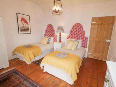 A bedroom with two single beds with yellow blankets and red patterned headboards at The Old Rectory Coach House in Rathmullan County Donegal