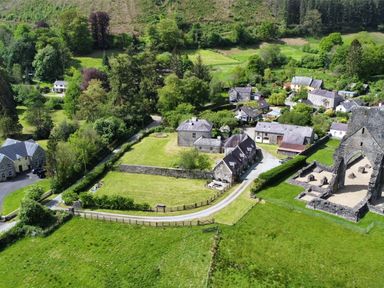An aerial view of a rural village with houses green fields trees and a stone ruin at Heron House in Talley near Llandeilo