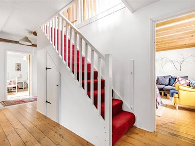 A hallway with red carpeted stairs and wooden floors at Heron House in Talley near Llandeilo