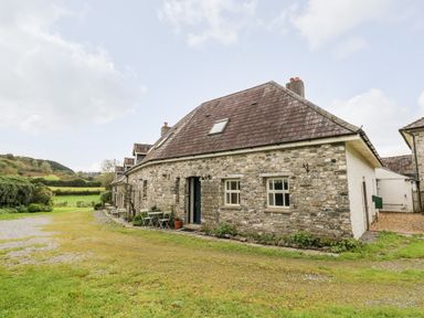 Stone cottage with small tables and chairs outside in grassy area at Heron House in Talley near Llandeilo
