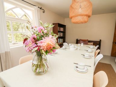 A dining room with a flower vase on a table set with cups and saucers at Heron House Talley near Llandeilo
