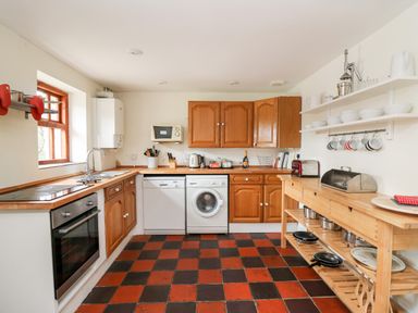 A kitchen with wooden cabinets white appliances and open shelving at Heron House in Talley near Llandeilo