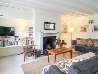 A living room with a fireplace a wooden chair and a television on a shelf at Buzzards Watch in Talley near Llandeilo