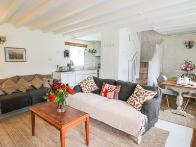 A living room with two sofas a coffee table with flowers and a dining table with chairs at Buzzards Watch in Talley near Llandeilo