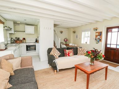 A living room with two sofas a wooden coffee table with flowers and an open kitchen area at Buzzards Watch Talley near Llandeilo