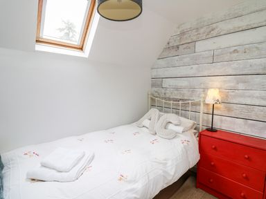 A bedroom with a bed with white bedding and folded towels a red chest of drawers and a skylight window at Buzzards Watch in Talley near Llandeilo