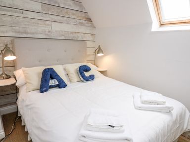 A bedroom with a bed with white bedding two bedside tables with lamps and folded towels on the bed at Buzzards Watch Talley near Llandeilo