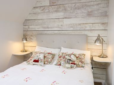 A bed with a grey headboard floral pillows and two metal bedside lamps at Buzzards Watch in Talley near Llandeilo