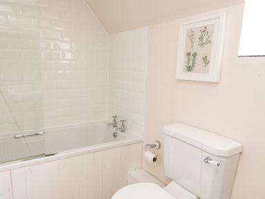 A bathroom with a bathtub and toilet and a framed botanical print on the wall at Buzzards Watch in Talley near Llandeilo