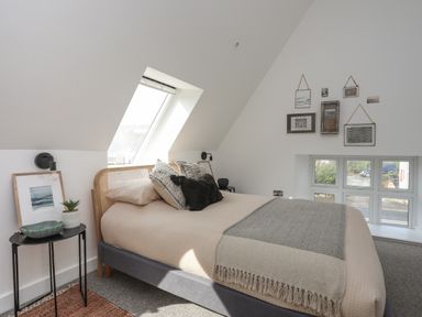 A bedroom with a bed under a skylight window and framed pictures on the wall at Ysgol Fach Little School in Benllech