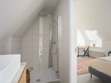 A bathroom with a shower and sink opening into a bedroom with a bed desk and chair at Ysgol Fach Little School in Benllech