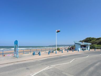 A beachside promenade with benches a Welsh flag and a small kiosk by the sea at Ysgol Fach Little School in Benllech