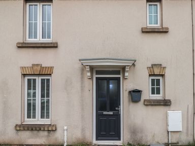 The front exterior of a house with a black door a black mailbox and four windows at 39 Mariners Quay in Port Talbot