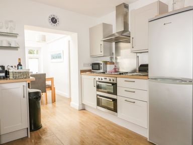 A kitchen with white cabinets a stainless steel oven microwave and refrigerator at Blacksmiths Cottage in Crantock